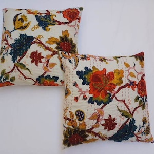 May include: Two white cotton pillow covers with a floral pattern in shades of red, orange, yellow, green, and blue. The floral pattern features intricate details and a traditional Indian style.