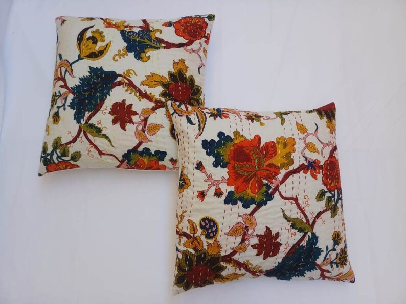 May include: Two white cotton pillow covers with a floral pattern in shades of red, orange, yellow, green, and blue. The floral pattern features intricate details and a traditional Indian style.