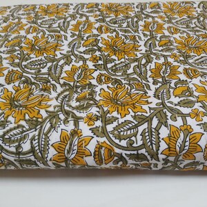 May include: White fabric with a repeating pattern of yellow and green floral designs.