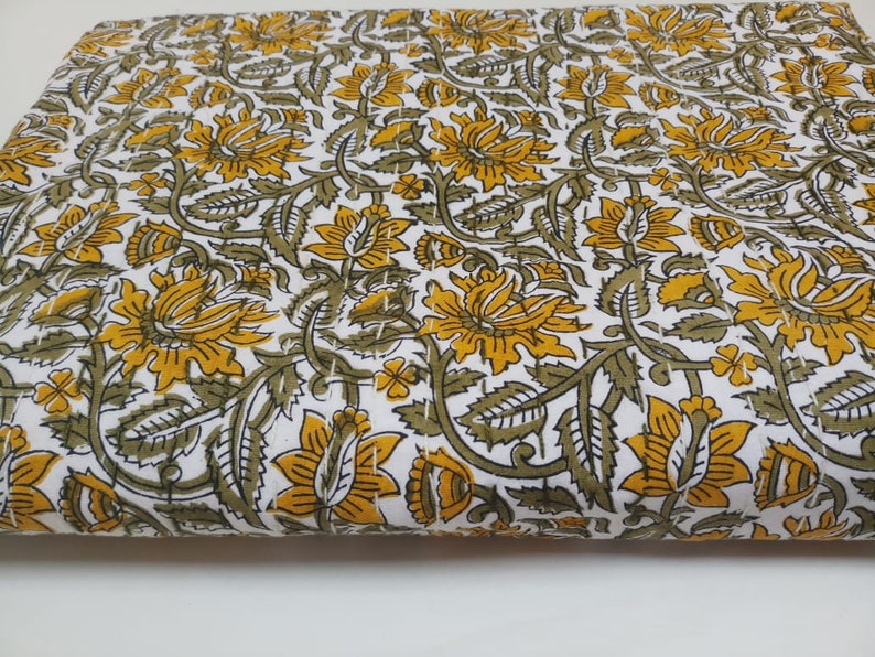 May include: White fabric with a repeating pattern of yellow and green floral designs.
