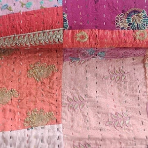 Pode incluir: Uma colcha de retalhos feita de v&aacute;rios tons de rosa e vermelho com detalhes intrincados de bordado. A colcha &eacute; feita de saris reciclados e &eacute; uma pe&ccedil;a de arte &uacute;nica e bela.