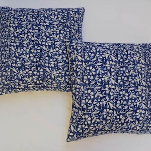 May include: Two blue and white patterned throw pillows with a floral design. The pillows are made of cotton and are perfect for adding a touch of color and style to any room.