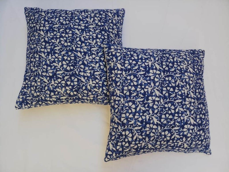 May include: Two blue and white patterned throw pillows with a floral design. The pillows are made of cotton and are perfect for adding a touch of color and style to any room.