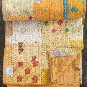 Könnte beinhalten: Eine gelbe und weiße Patchwork-Decke mit aufwendigen Stickereien und Nähten. Die Decke besteht aus verschiedenen Stoffen und zeigt eine Vielzahl von floralen und geometrischen Mustern.