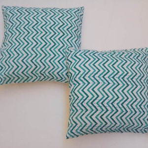 May include: Two green and white chevron patterned throw pillows. The pillows are made of a soft, cotton fabric and have a subtle sheen.