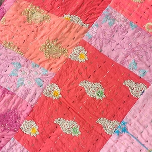 Pode incluir: Uma colcha de retalhos feita de diferentes tecidos em tons de rosa e vermelho. A colcha &eacute; decorada com bordados intrincados em fio de ouro e prata. A colcha &eacute; feita de uma variedade de tecidos, incluindo algod&atilde;o e seda.