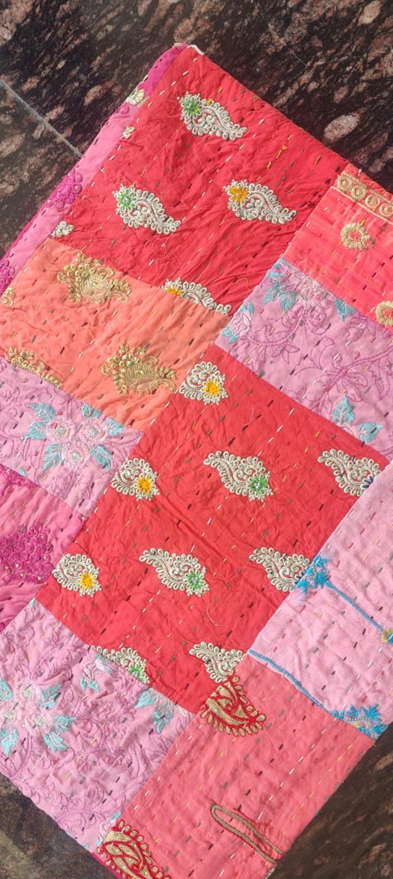 Pode incluir: Uma colcha de retalhos feita de diferentes tecidos em tons de rosa e vermelho. A colcha &eacute; decorada com bordados intrincados em fio de ouro e prata. A colcha &eacute; feita de uma variedade de tecidos, incluindo algod&atilde;o e seda.