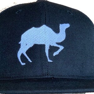 May include: A black baseball cap with a light blue camel silhouette embroidered on the front.