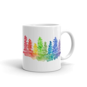 May include: White ceramic mug with a watercolor design of a rainbow-colored forest. The trees are painted in shades of red, orange, yellow, green, blue, and purple.