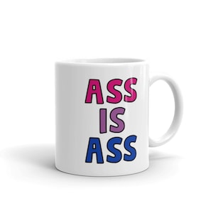 Puede incluir: Taza de cerámica blanca con el texto "ASS IS ASS" en rosa, morado y azul.