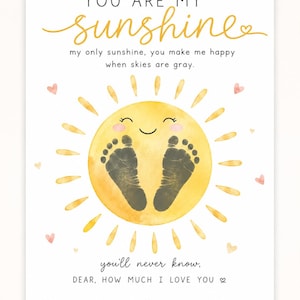 以下が含まれることがあります： 「YOU ARE MY sunshine」の文字が書かれた白いプリント。赤ちゃんの手形と「my only sunshine, you make me happy when skies are gray」の文字が描かれた、黄色の水彩画の太陽が特徴です。
