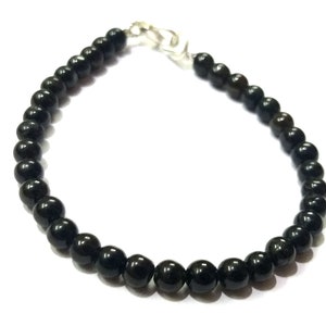 May include: A black beaded bracelet with a silver clasp.