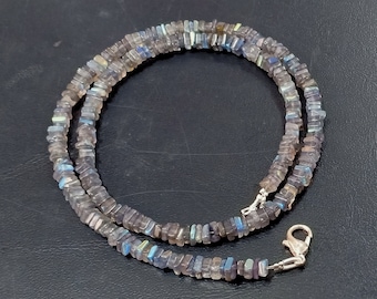 May include: A silver necklace with a silver clasp. The necklace is made of small, square-shaped labradorite beads in shades of gray, blue, and green.