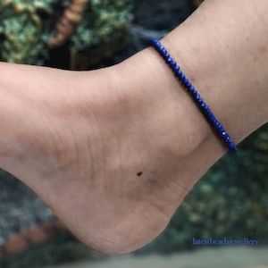 Può includere: Un braccialetto per caviglia con piccole perle di pietra preziosa blu sfaccettate.