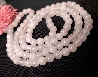 Può includere: Una collana mala composta da perle di quarzo rosa. Le perle sono lisce e lucidate, con un leggero bagliore.