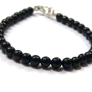 May include: A black beaded bracelet with a silver clasp.