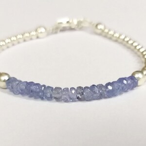 May include: A silver bracelet with a row of light blue gemstone beads.