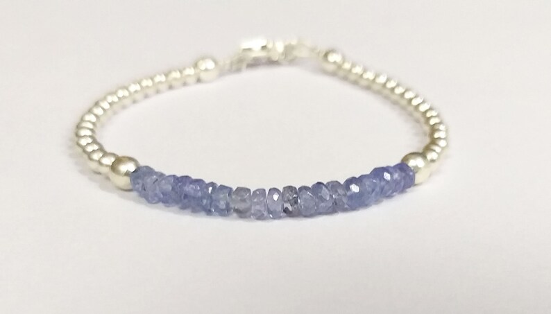 May include: A silver bracelet with a row of light blue gemstone beads.