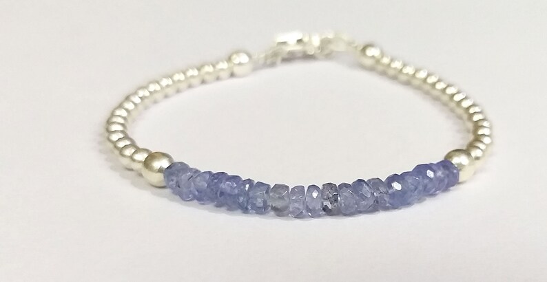 May include: A silver bracelet with a row of light blue gemstone beads and silver spacer beads.
