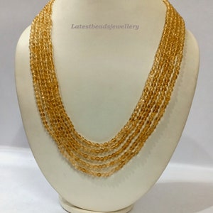 May include: A multi-strand necklace made of small, round, golden-brown beads. The necklace is displayed on a white mannequin bust. The text "Latestbeadsjewellery" is visible on the bust.