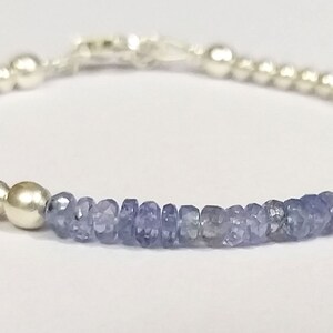 May include: A silver bracelet with a row of light blue gemstone beads.