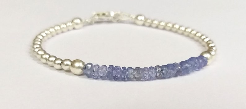 May include: A silver bracelet with a row of light blue gemstone beads.