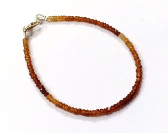 May include: A brown and orange gemstone bracelet with a silver clasp.