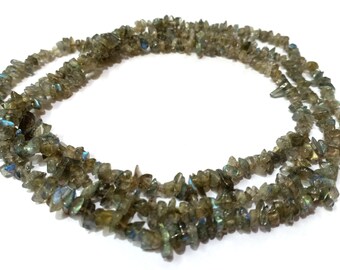 May include: A strand of iridescent green and blue labradorite chip beads. The beads are irregular in shape and have a natural, rough texture.