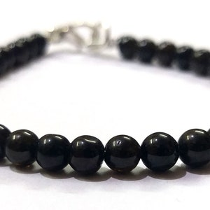 May include: A black beaded bracelet with a silver clasp.
