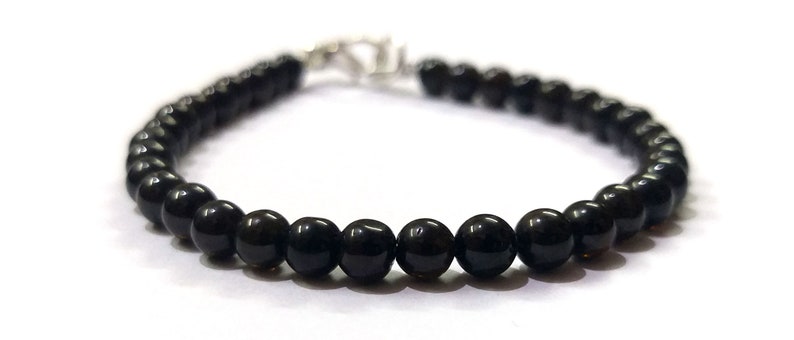 May include: A black beaded bracelet with a silver clasp.