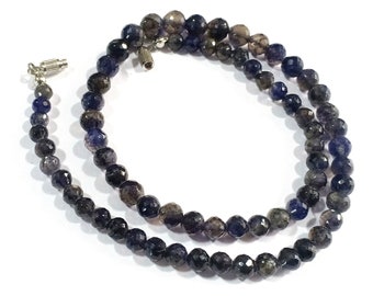 May include: A necklace made of dark blue faceted gemstone beads. The beads are strung on a silver chain and have a silver clasp.