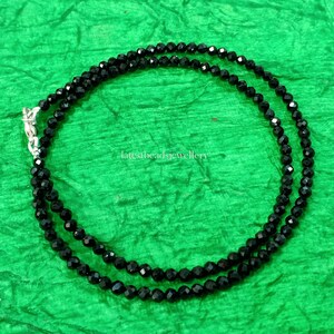 Op de afbeelding: Een zwarte kralenketting met een zilveren sluiting. De ketting is gemaakt van kleine, gefacetteerde kralen en is ongeveer 45 cm lang.