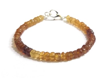 May include: A brown and yellow gemstone bracelet with a silver clasp.