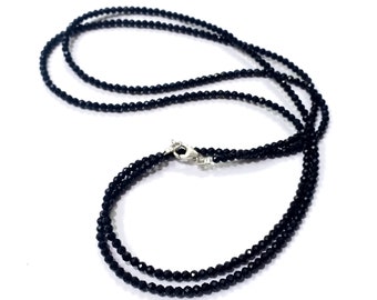 May include: A black beaded necklace with a silver clasp. The necklace is made of small, round beads and is approximately 18 inches long.