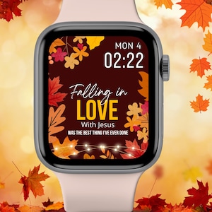 May include: A pink Apple Watch with a brown background featuring a fall-themed design with leaves and lights. The watch face displays the text "Falling in LOVE With Jesus WAS THE BEST THING I'VE EVER DONE" and the time "MON 4 02:22".