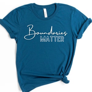 May include: Teal blue t-shirt with white text that reads "Boundaries Matter" in a cursive font.