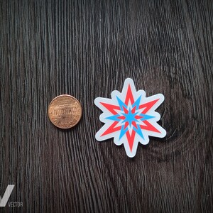 May include: A sticker with a starburst design in red, light blue, and white. A penny is next to the sticker for size comparison. The sticker is on a dark wood-grain surface. The logo "Visibly Vector" is in the bottom left corner.