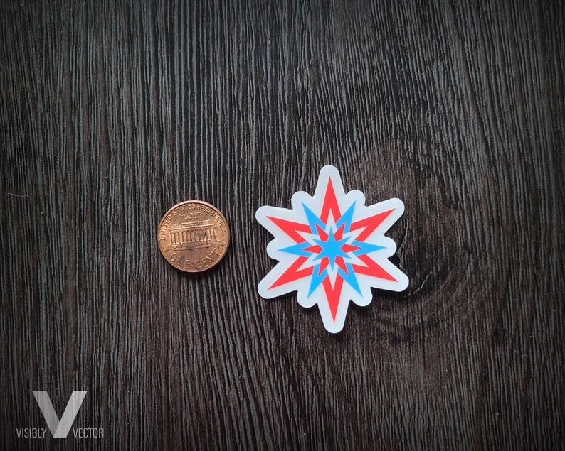May include: A sticker with a starburst design in red, light blue, and white. A penny is next to the sticker for size comparison. The sticker is on a dark wood-grain surface. The logo "Visibly Vector" is in the bottom left corner.