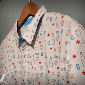 May include: White polo shirt with a blue and red pattern of stars, cans, and bottles. The shirt has a button-up collar and a button placket.