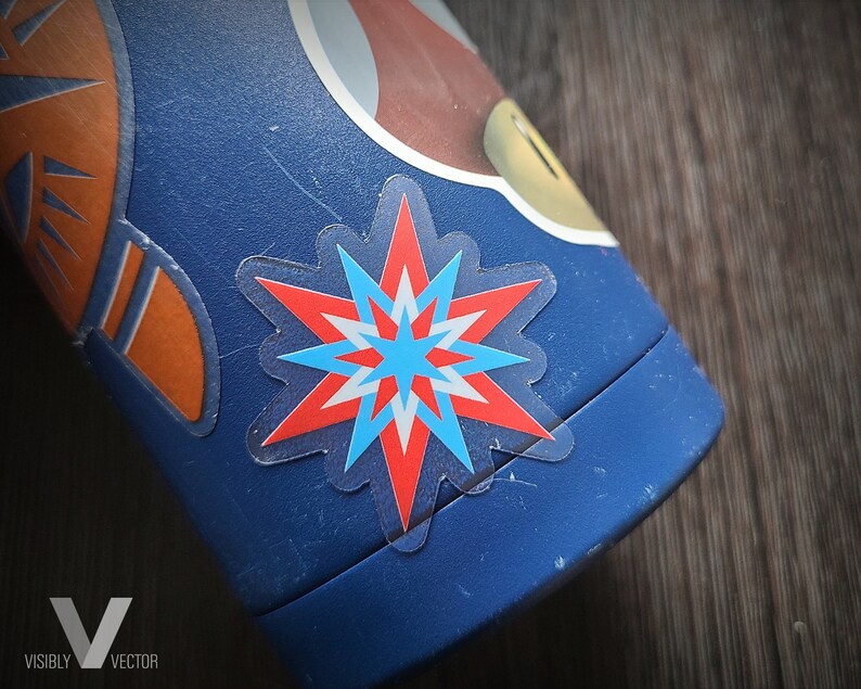 May include: Close-up of a blue water bottle with a starburst sticker in red, white, and blue. The bottle also features orange and white graphics. The sticker is transparent and has a star shape.