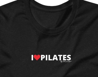 Pode incluir: Camiseta preta com texto branco que diz "I ♥ PILATES" com um coração vermelho e o símbolo de marca registrada e "PILATAY" em texto menor abaixo.