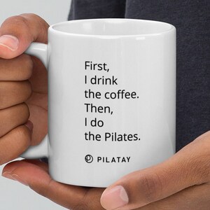May include: White ceramic mug with black text that reads "First, I drink the coffee. Then, I do the Pilates."  The text is centred on the mug.  The mug has a black logo that reads "PILATAY" at the bottom.