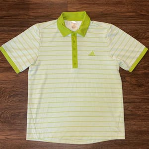 May include: A light green and white striped polo shirt with a lime green collar, sleeve edges, and button placket. The Adidas logo is embroidered on the right chest.