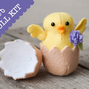 May include: A felt craft kit to make a yellow chick in an eggshell. The chick has black eyes, an orange beak, and a purple flower. The kit includes all the materials needed to make the chick.