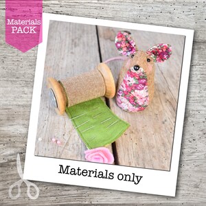 May include: A craft materials pack featuring a handmade mouse with floral ears and body, a wooden spool with burlap, a green felt pin cushion, and a pink felt rose. The image includes the text "Materials Pack" and "Materials only".