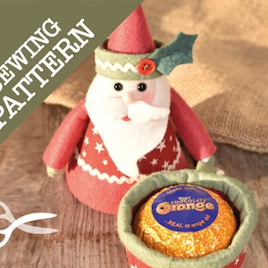 Peut inclure: Patron de couture pour une décoration de Noël représentant le Père Noël avec un chapeau rouge, une barbe blanche et un corps à motifs rouges et blancs. L'ornement tient un petit panier contenant une orange au chocolat.