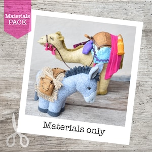 May include: Felt camel and donkey figures with decorative saddles and accessories. The camel is tan, and the donkey is blue. The image includes the text "Materials Pack" and "Materials only".