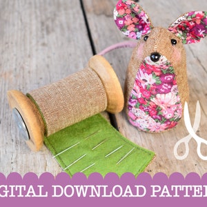Puede incluir: Un patrón de descarga digital para coser un lindo juguete de ratón. El ratón es marrón con tela floral rosa en su cuerpo y orejas. La imagen también muestra un carrete de hilo, un trozo de fieltro verde con agujas y un par de tijeras.