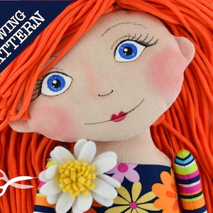 May include: Sewing pattern for a handmade doll with long orange hair, blue eyes, and a floral dress. The doll is holding a white daisy with a yellow center.