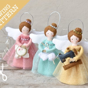 Puede incluir: Tres adornos de ángel de fieltro con alas, cada uno sosteniendo un objeto de artesanía diferente: una máquina de coser, un ganchillo y lana, y un aro de bordado. Los ángeles llevan faldas de tul de color rosa, azul verdoso y dorado.